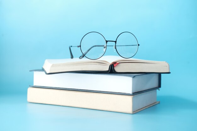 Pile de livres et de lunettes sur fond bleu