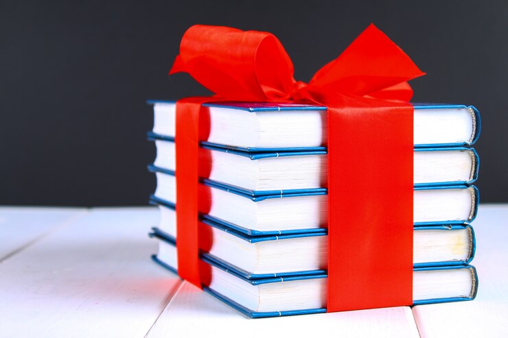 Une pile de livres noués avec un ruban rouge sur une table en bois blanche. cadeau sur fond de tableau