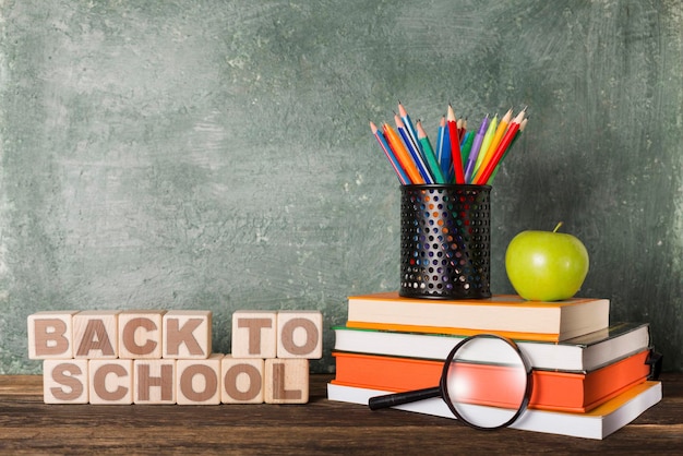 Pile de livres et papeterie et slogan retour à l'école