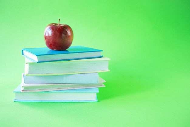 Une pile de livres et une pomme sur un espace de copie de fond vert