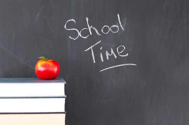 Pile de livres avec une pomme rouge et un tableau noir avec &quot;temps scolaire&quot; écrit dessus