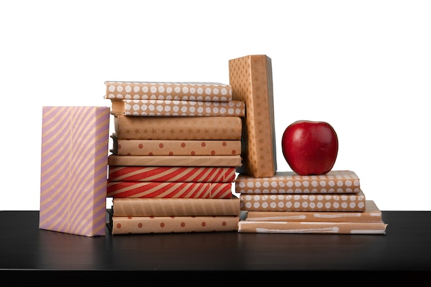 Pile de livres et pomme sur table contre fond blanc