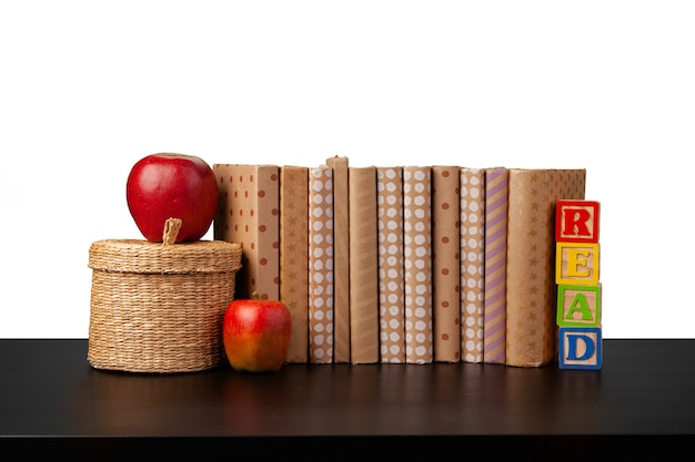 Pile de livres et pomme sur table contre fond blanc