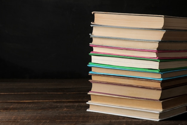 Une pile de livres sur une table en bois marron et sur fond noir. Vieux livres. Éducation. l'école. étude Avec espace pour les inscriptions