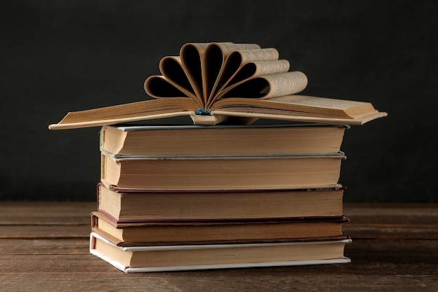 Une pile de livres sur une table en bois marron et sur fond noir. Vieux livres. Éducation. l'école. étudier