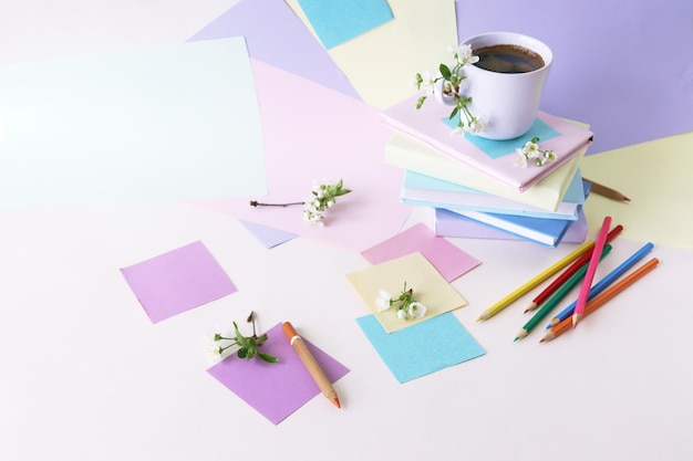 Une pile de livres une tasse de café des crayons des blocs-notes et des brindilles de fleurs de cerisier sur la table