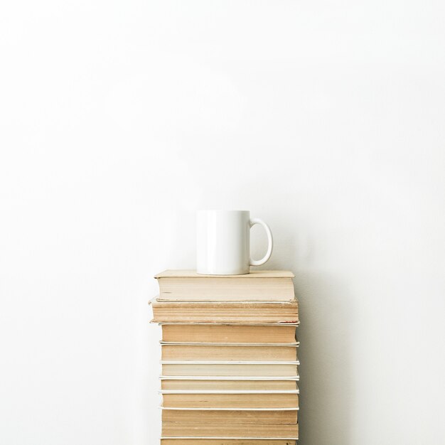 Pile de livres et tasse de café sur une surface blanche