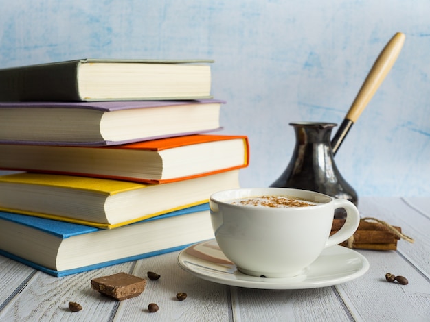 Une pile de livres et une tasse de cappuccino