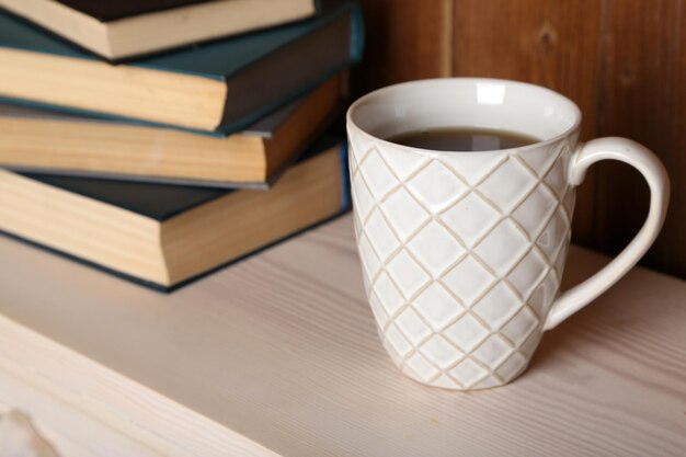 Pile de livres avec tasse sur table et fond en bois