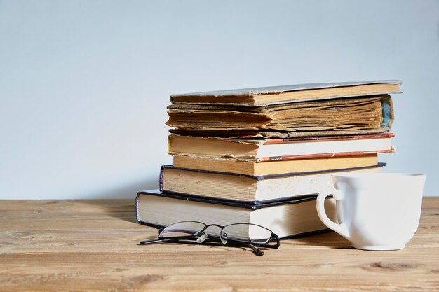 Pile de livres avec une tasse et des verres à côté. Espace pour le texte. Le concept de formation et d'éducation.