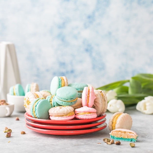 Pile de macarons français ou italiens colorés sur plaque rouge. Dessert servi avec thé de l'après-midi ou pause café. Beau fond de repas