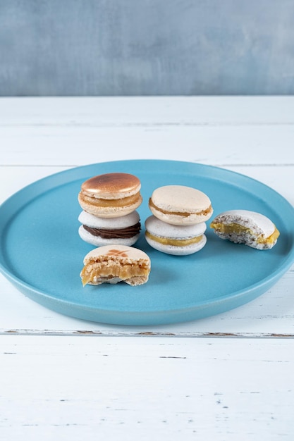 Pile de macarons remplis de dulce de leche et de ganache au chocolat à côté de deux macarons avec piqûres verticales