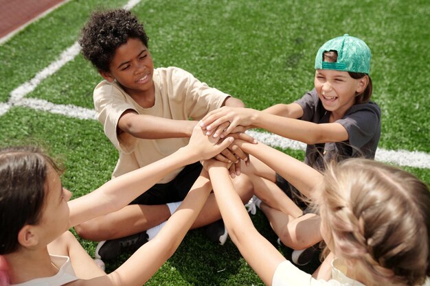 Photo pile de mains de quatre jeunes amis d'école et joueurs de football