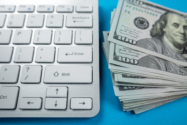 Pile de nombreux dollars américains sur un clavier d'ordinateur portable blanc