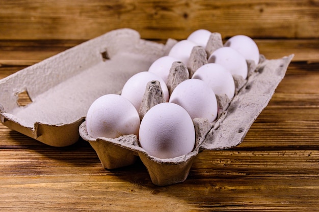 Pile des oeufs de poule dans le bac à papier sur la table en bois