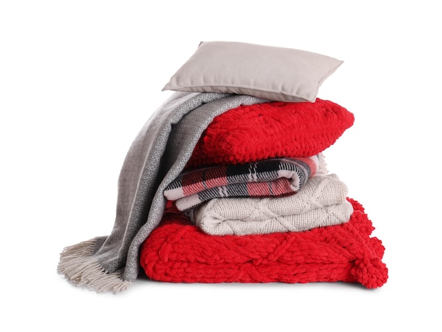 Pile d'oreillers et plaids chauds pliés sur fond blanc