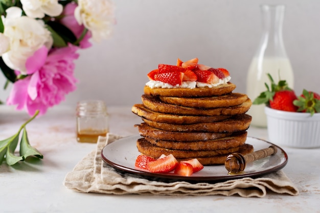 Pile de pain grillé avec du fromage cottage, du miel et des fraises pour le petit déjeuner.