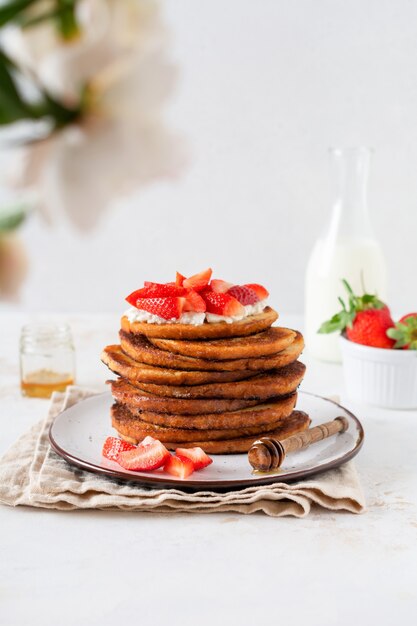 Pile de pain grillé avec du fromage cottage, du miel et des fraises pour le petit déjeuner.