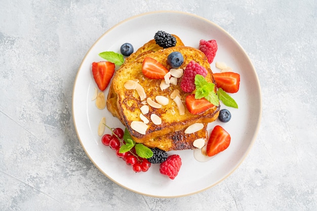 Une pile de pain perdu sur une assiette avec des pétales d'amandes de baies fraîches Délicieux petit-déjeuner Espace de copie