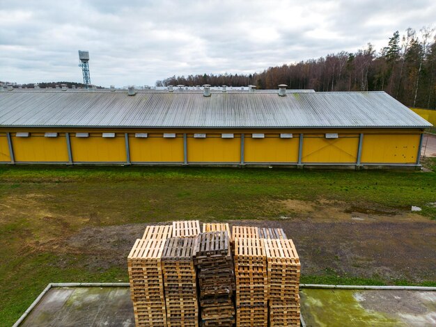 Pile de palettes en bois vue aérienne Zone de stockage de palettes en plein air sous le toit à côté de l'élevage de poulets Piles de palettes de fret Eurotype dans une installation de recyclage des déchets