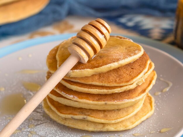 Pile de petites crêpes au sirop De savoureuses crêpes du matin versées avec du miel