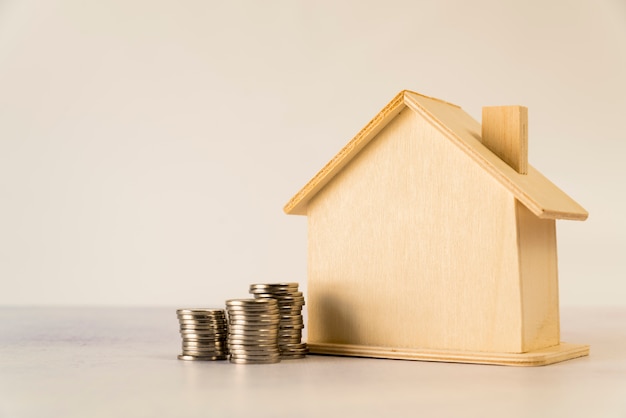 Photo pile de pièces de monnaie près de la maison en bois sur fond blanc