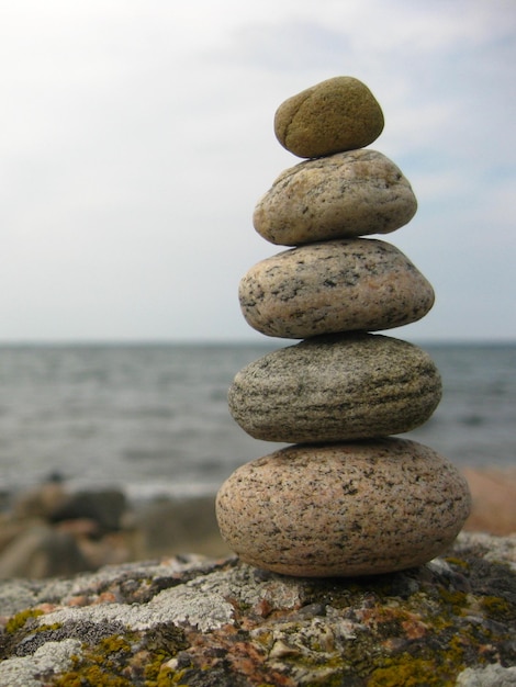 Une pile de pierres par la mer contre un ciel nuageux
