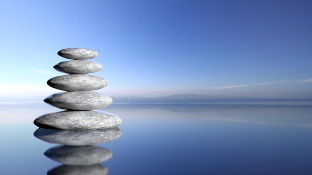 Pile de pierres zen de grande à petite dans l'eau avec ciel bleu et fond de paysage paisible