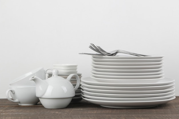 Une pile de plats. vaisselle sur une table en bois marron. assiettes et couverts, tasses et bouilloire.