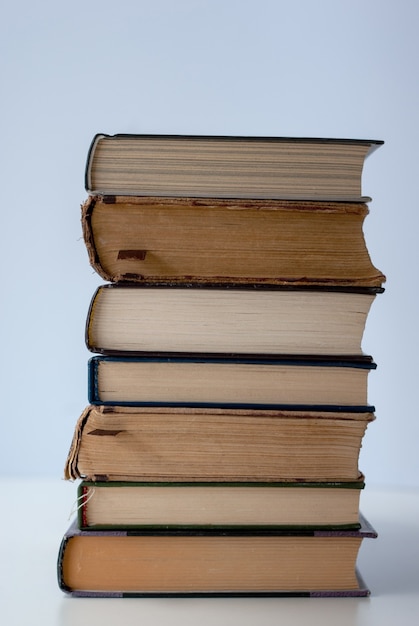 Pile de plusieurs vieux livres sur fond clair.