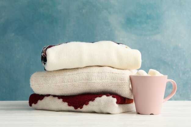 Pile de pulls contre avec tasse de chocolat chaud