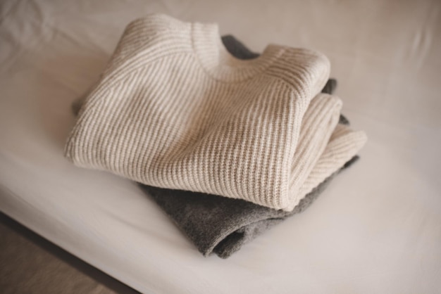 Pile de pulls textiles en laine tricotée sur une couverture blanche dans le lit à la maison chambre close up hiver saison confortable