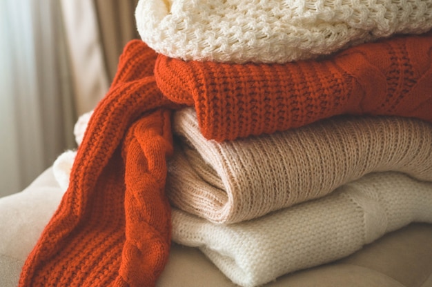 Une pile de pulls tricotés à l'intérieur du salon. Le concept du confort automne hiver