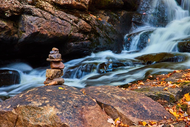 Pile de rochers cairn sur le bord de la rivière en cascade avec des feuilles d'automne