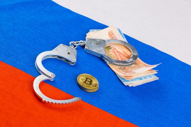 Pile de roubles papier russe devise et méné bitcoin enchaînés avec des menottes sur fond de drapeau russe concept de loi d'interdiction de crypto