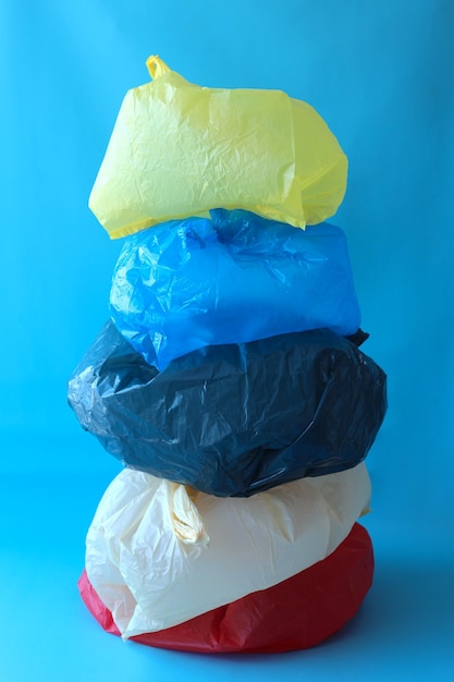 Pile de sacs en plastique jetables colorés sur fond bleu.