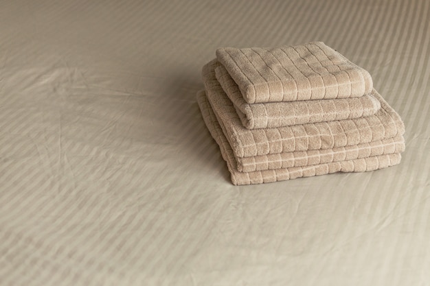 Pile de serviette d&#39;hôtel beige sur le lit à l&#39;intérieur de la chambre. Vintage tonifiant