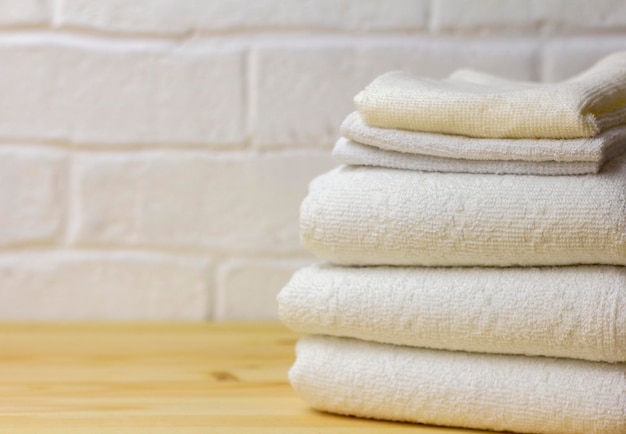 Une pile de serviettes blanches et propres se trouve sur une table en bois.