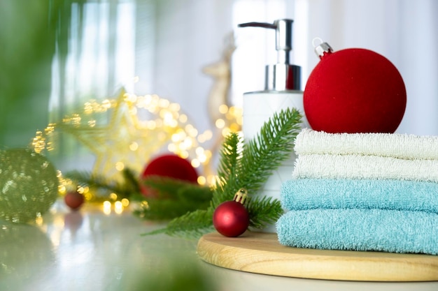 Une pile de serviettes bleues et blanches pliées sur la table branches de sapin boules de Noël et lumières de Noël massage SPA ou salon de beauté soins de la peau et soins du corps dans la variante de Noël ou du Nouvel An