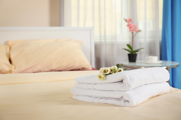Pile de serviettes et de fleurs sur le lit dans la chambre d'hôtel