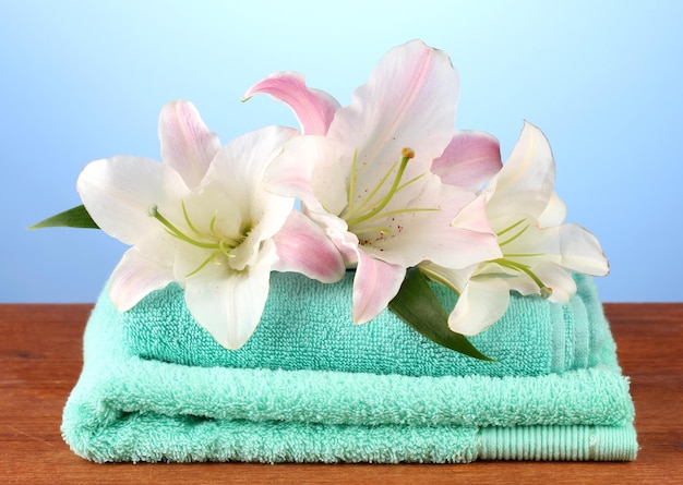 Pile de serviettes avec lys rose sur fond bleu