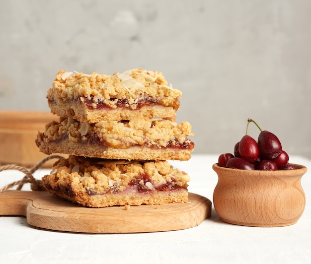 Pile de tarte crumble cuite au four avec garniture aux fruits et saupoudrée d'amandes râpées sur planche de bois