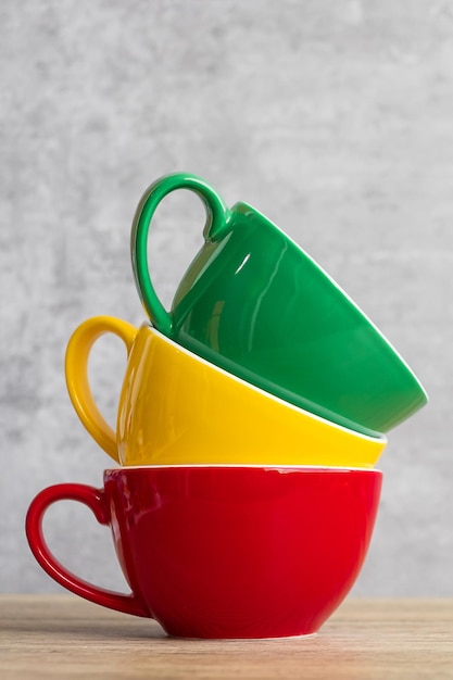 Pile de tasses à café colorées sur fond de mur au café Tasse en céramique de couleur vert jaune et rouge sur la table à la maison Concept de la journée internationale du café