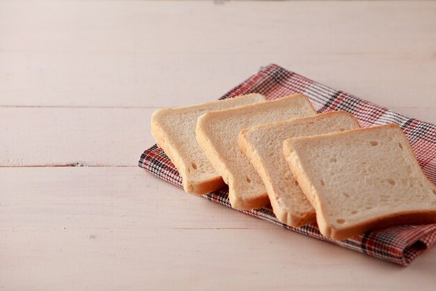 Une pile de toasts de pain tranché sur fond de bois blanc