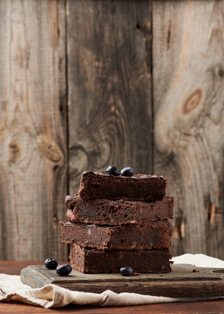 Pile de tranches carrées de gâteau au chocolat brownie aux noix sur une surface en bois