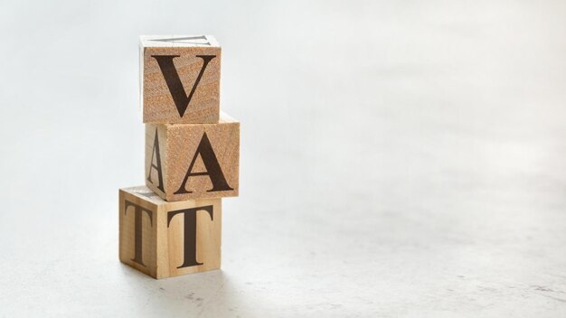 Pile avec trois cubes en bois - lettres TVA signifiant taxe sur la valeur ajoutée sur eux, espace pour plus de texte/images sur le côté droit.