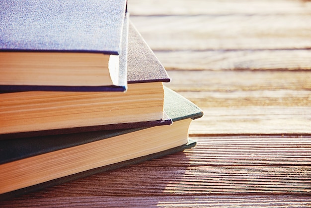 Pile de trois vieux livres en contre-jour sur table en bois, mise au point sélective