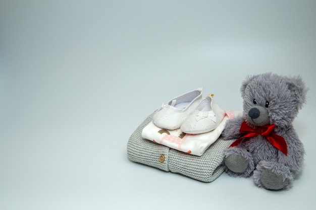 Une pile de vêtements et accessoires pour bébé avec ours en peluche