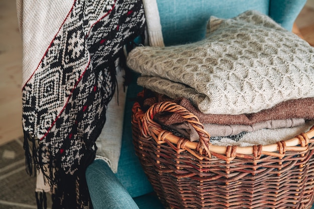 Pile de vêtements chauds tricotés sur un panier en osier