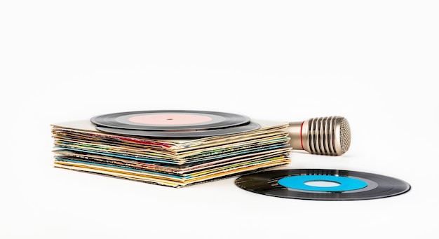 Photo une pile de vieux disques vinyles et un microphone pour karaoké sur fond blanc